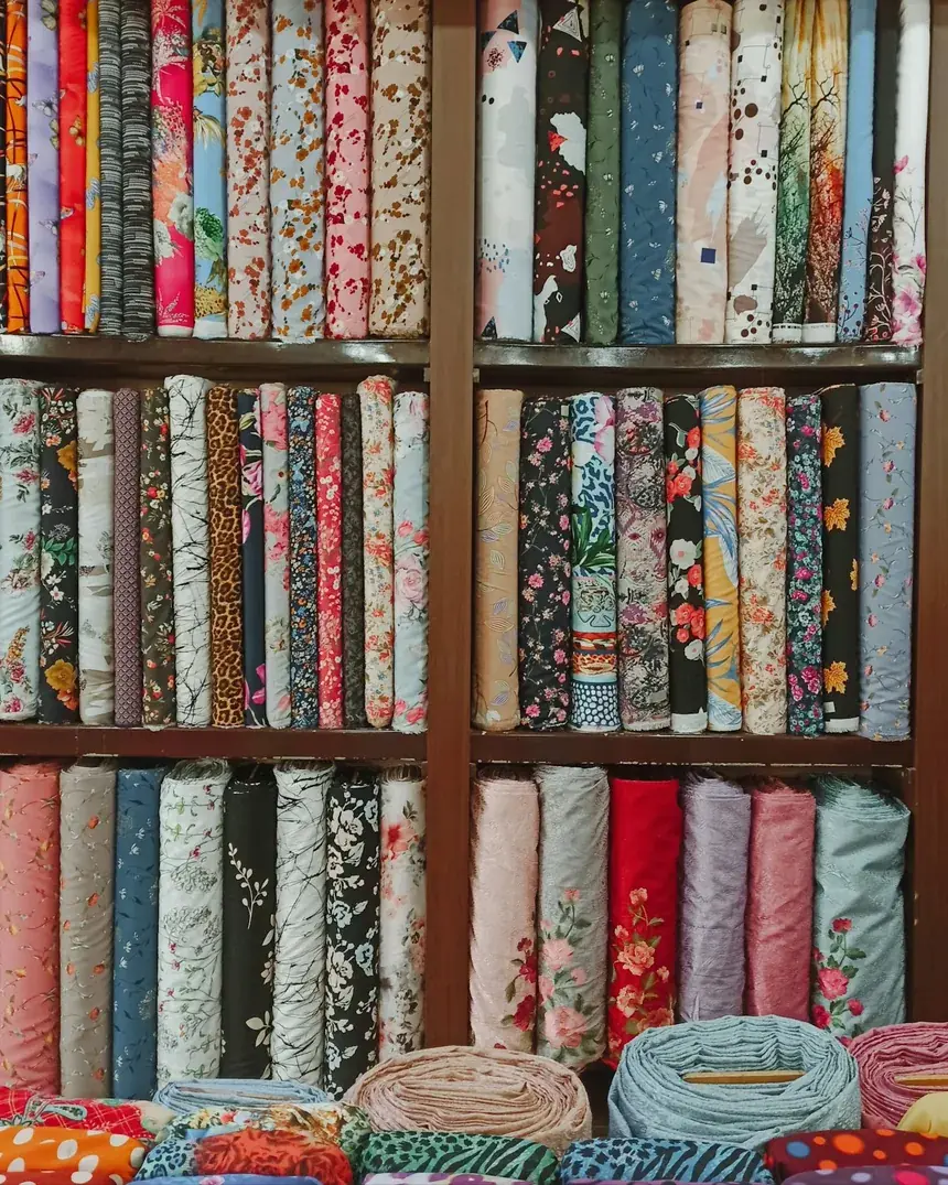 Estantería de taller con rollos de tejidos de tapicería de distintos colores
