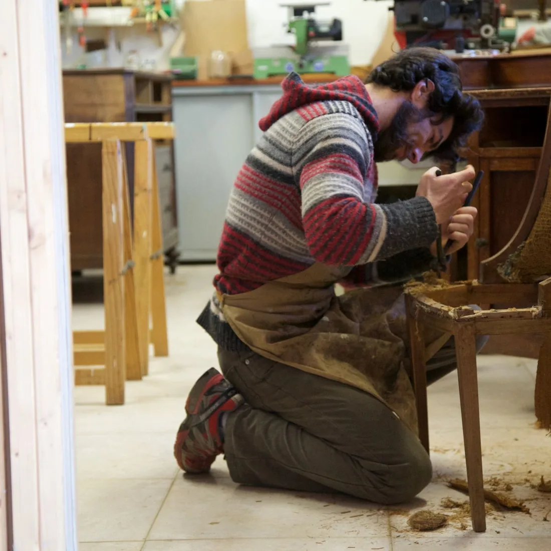 Taller de tapicería: restauración de una silla de madera con herramientas sobre el banco de trabajo